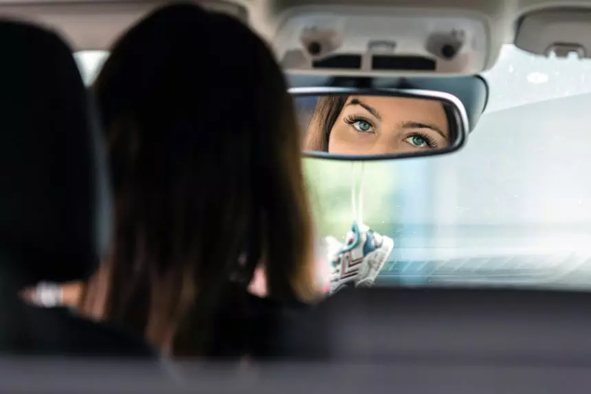 the beautiful eyes of the young driver woman are reflected in the rear view mirror
